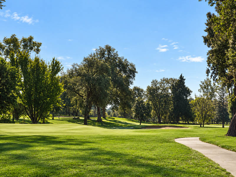 Scenic fairway and cart path at Plumas Lake Golf Club surrounded by mature Sacramento Valley trees.